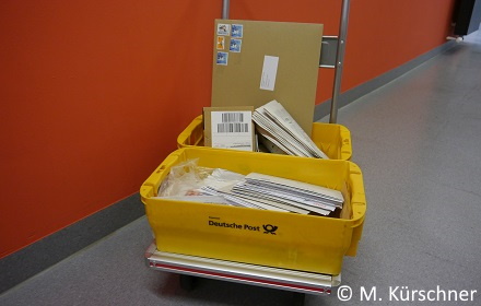 2 gelbe Postboxen auf einem Rollwagen