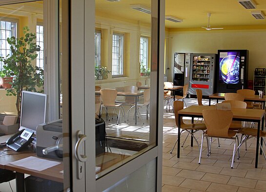 Besucherraum der JVA Hohenleuben mit Kanzel im Vordergrund und Besuchertischen. Im hinteren Bereich des Raumes befinden sich Verkaufsautomaten.