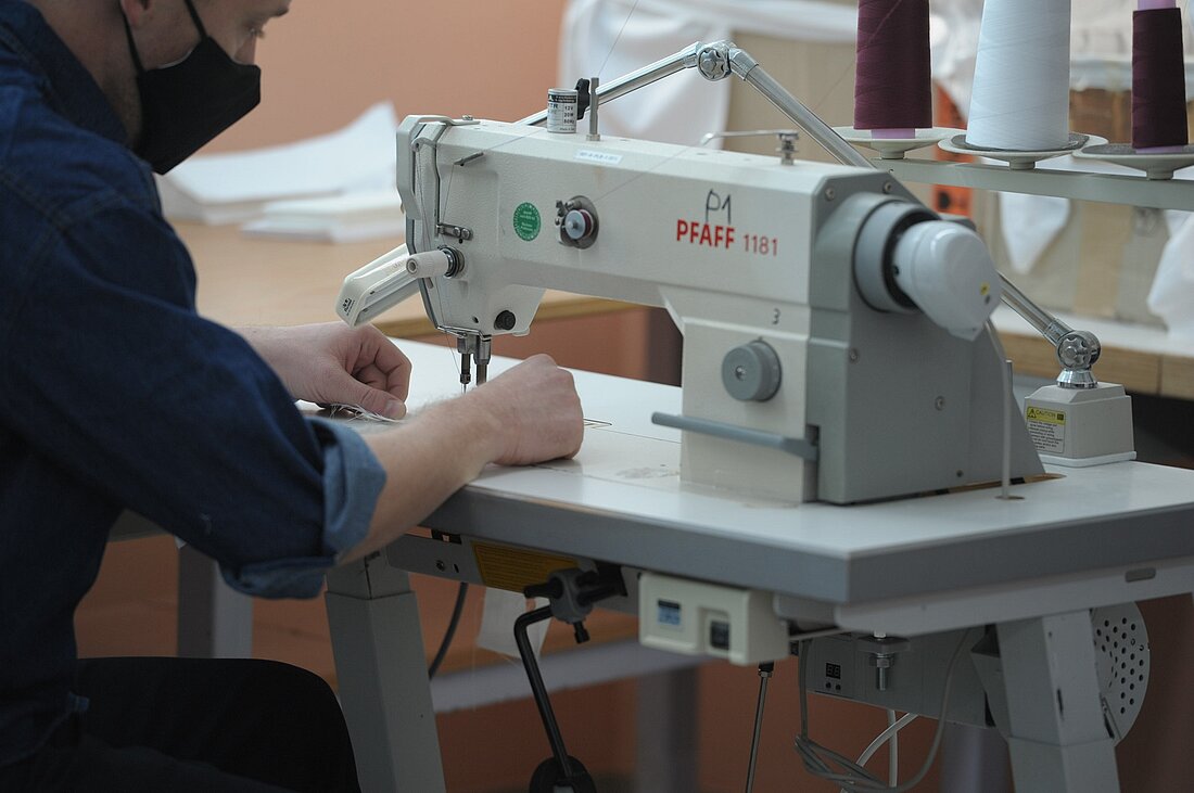 ein Gefangener näht an einer Nähmaschine