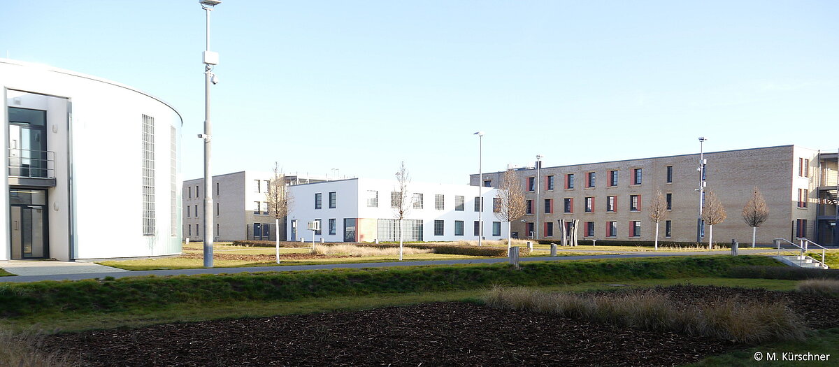Innengelände der Jugendstrafanstalt mit Blick auf das Kirchengebäude mit Bücherrei. Im Hintergrund eines der vier Hafthäuser der Anstalt.